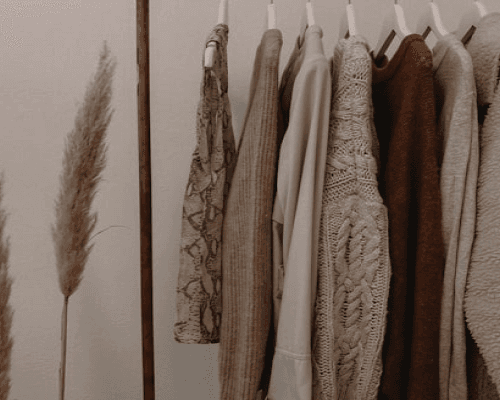 Hand-knitted garments on a wooden rail